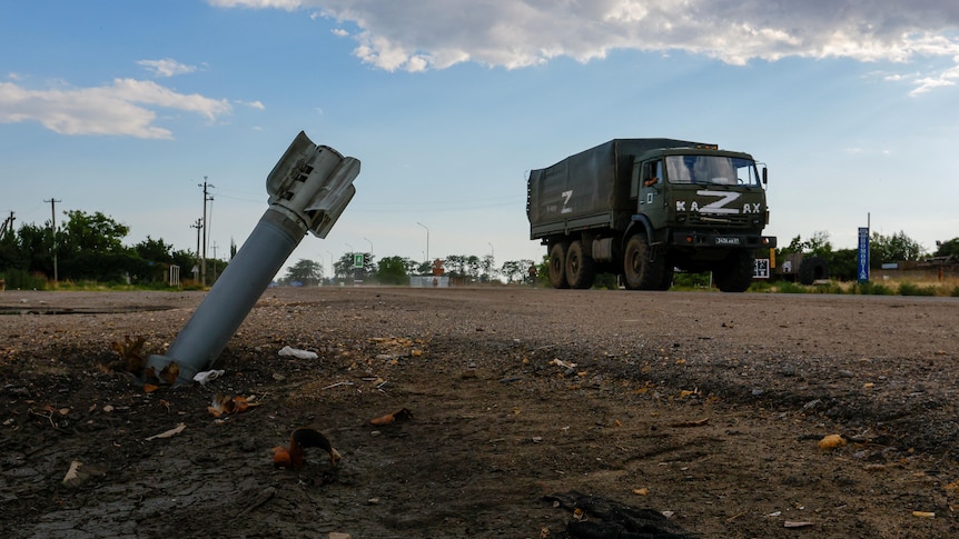 A Russian military truck drives past an unexploded munition.