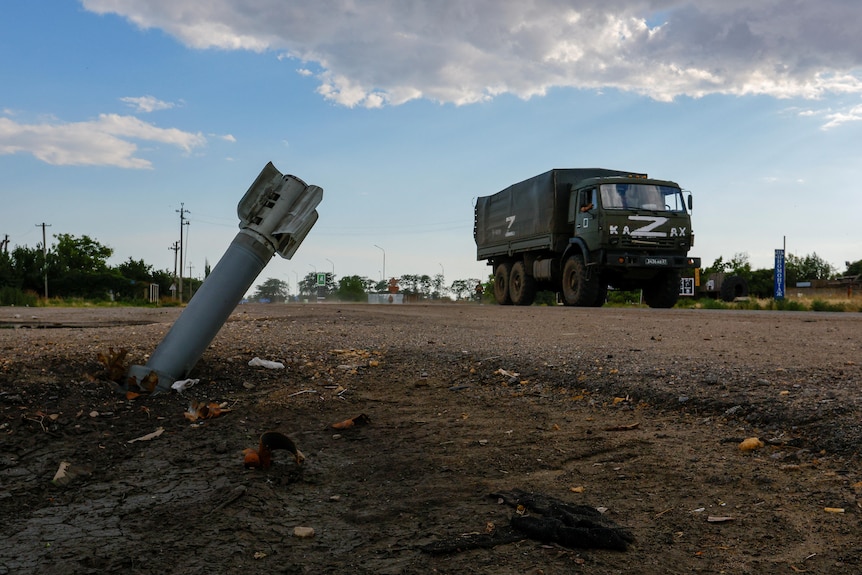 A Russian military truck drives past an unexploded munition.