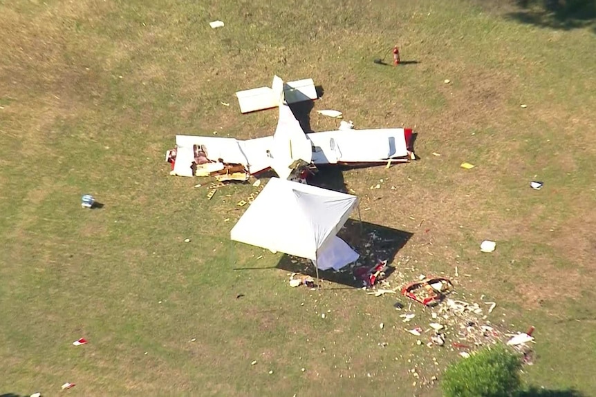 A crashed plane on a grassy backyard.