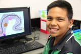Indigenous primary school student at his computer, smiling