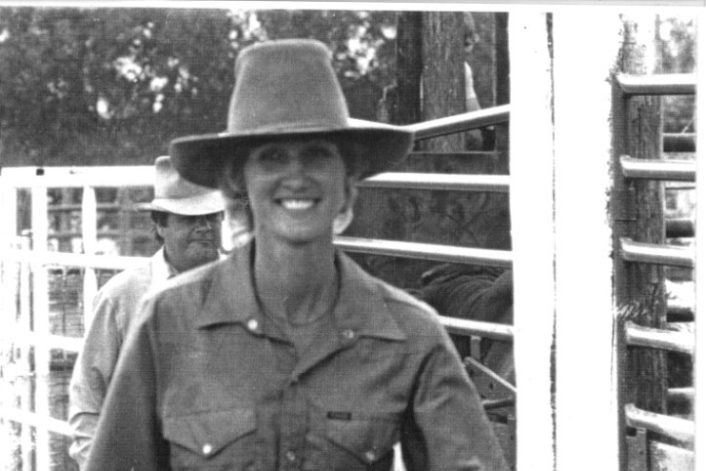 A woman wearing a cowboy hat smiles at the camera
