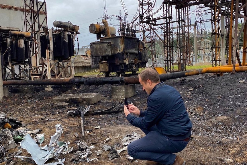 Nigel Pavoas is bent down among the remains of a power station in Kharkiv.