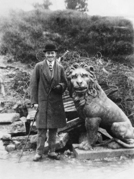 Unidentified man stands beside one of two carved lions at the Menin Gate in 1920.