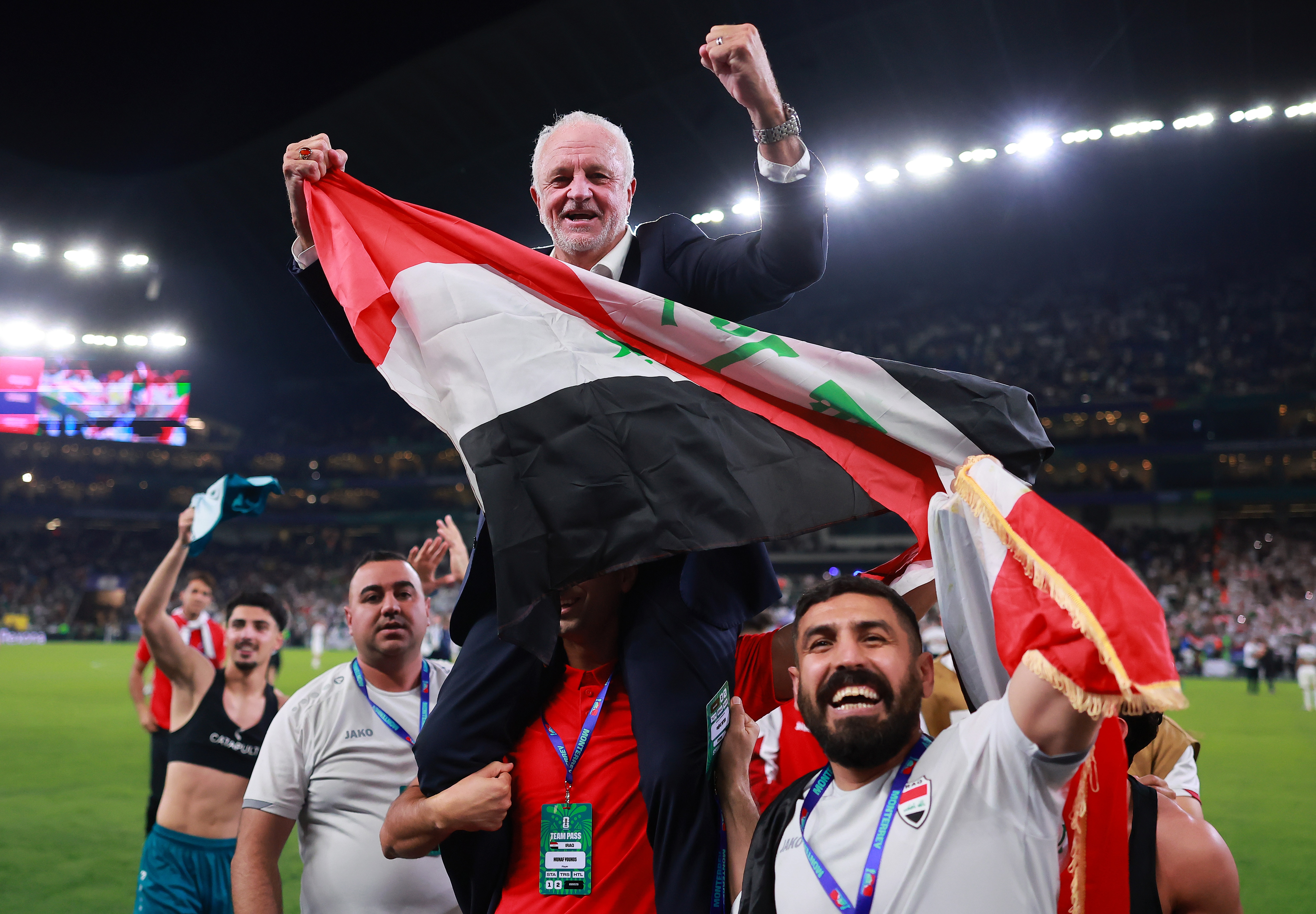 El entrenador de fútbol masculino de Irak, Graham Arnold, se sienta sobre los hombros de su equipo de entrenadores y ondea la bandera iraquí.