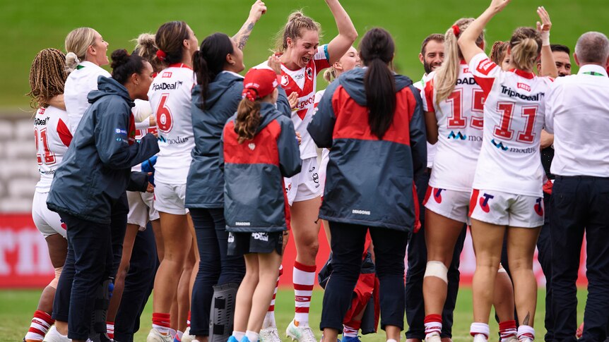 A group of NRLW players celebrate a victory with the team song 