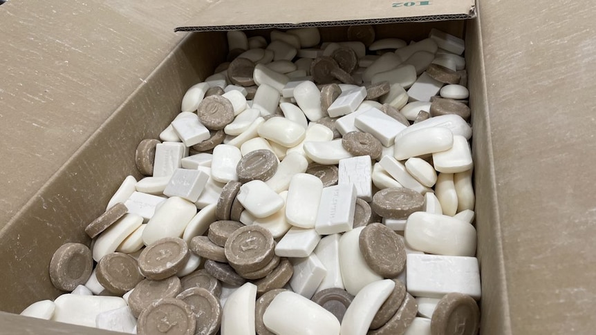 a large box full of brown and white bars of soap with minor signs of use