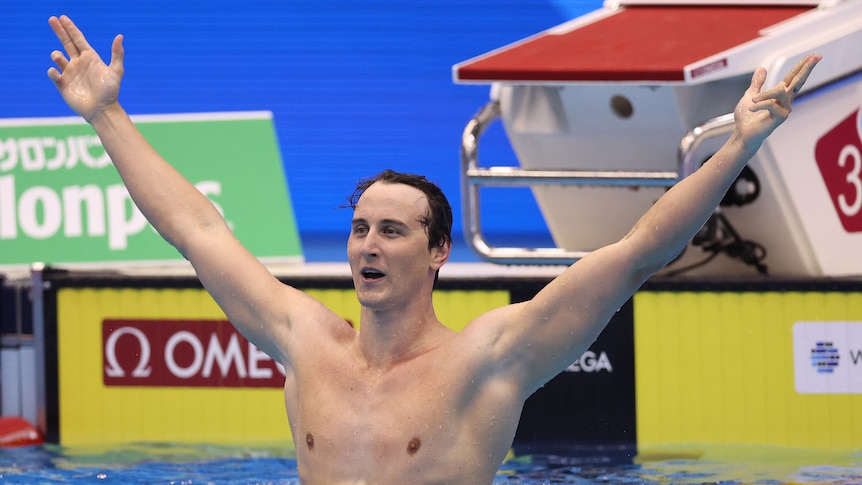 An Australian swimmer raises his arms in the pool after winning a gold medal.