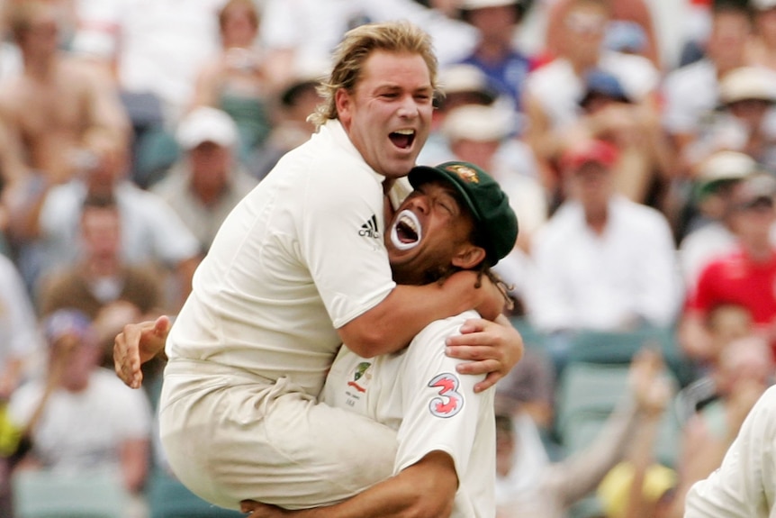 Two men in cricket whites embrace