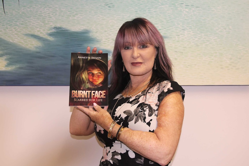 A woman holds a book up in front of her