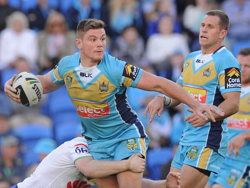 Paul Carter of the Titans looks to pass the ball in the tackle during the round 18 NRL match between the Gold Coast Titans and the Canberra Raiders