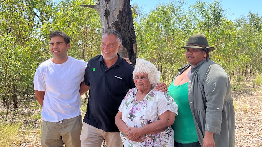 stan grant stands with his arm around a younger man and an older woman