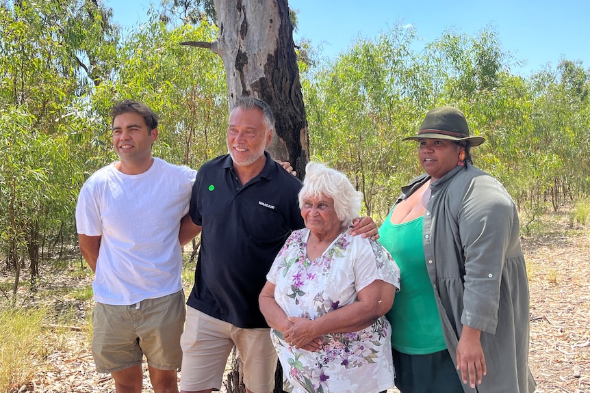 stan grant stands with his arm around a younger man and an older woman