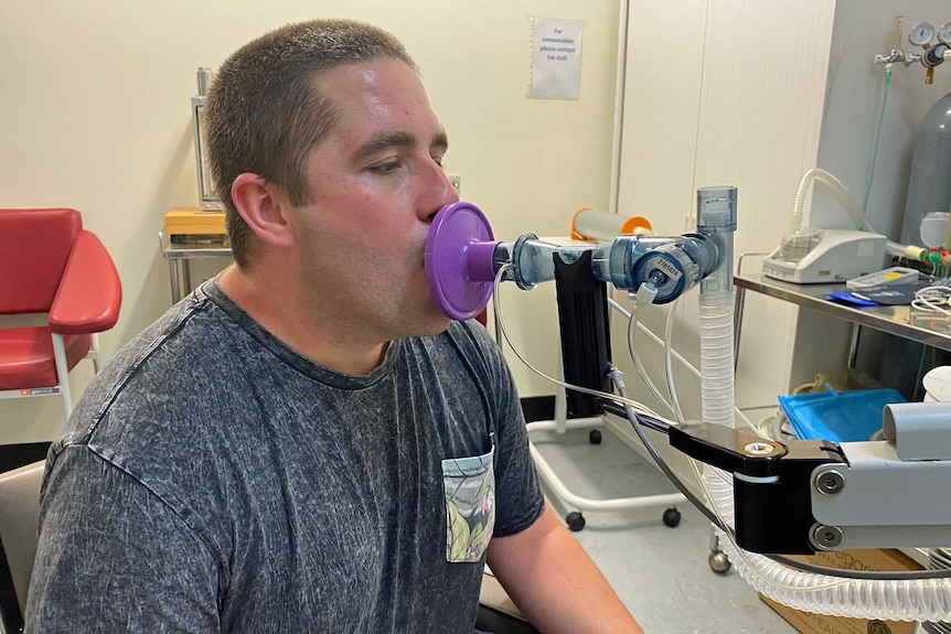 A man breaths into a plastic tube in a hospital.