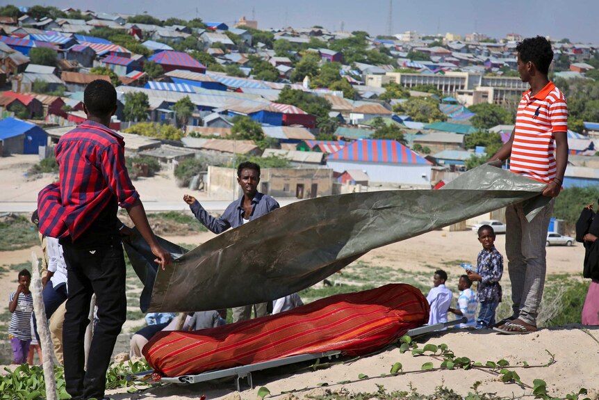 Somali men carry a covered body of a victim.
