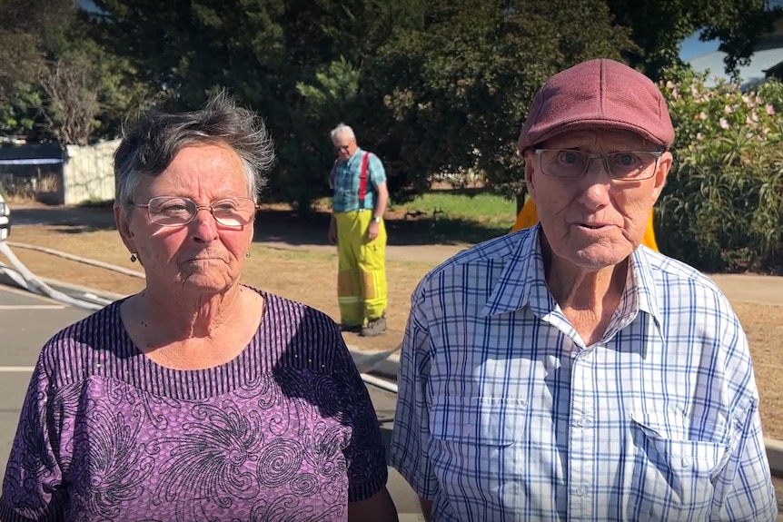 A woman with black hair in a purple top and a man with a purple cap in a blue shirt. Both have glasses