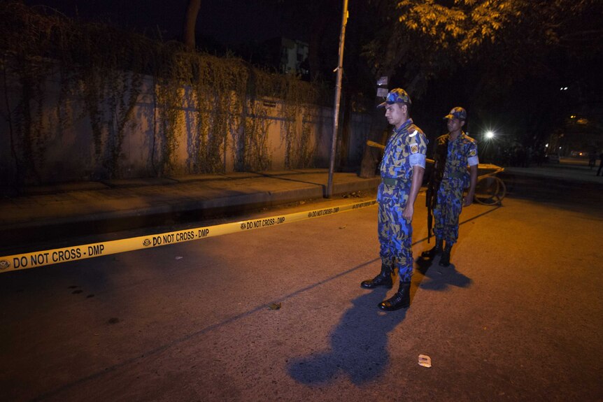 Bangladeshi police stand guard at the site where an Italian aid worker was gunned down in Dhaka