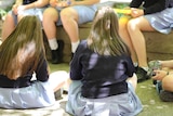 Unidentifiable teenage girls eat in a school yard.