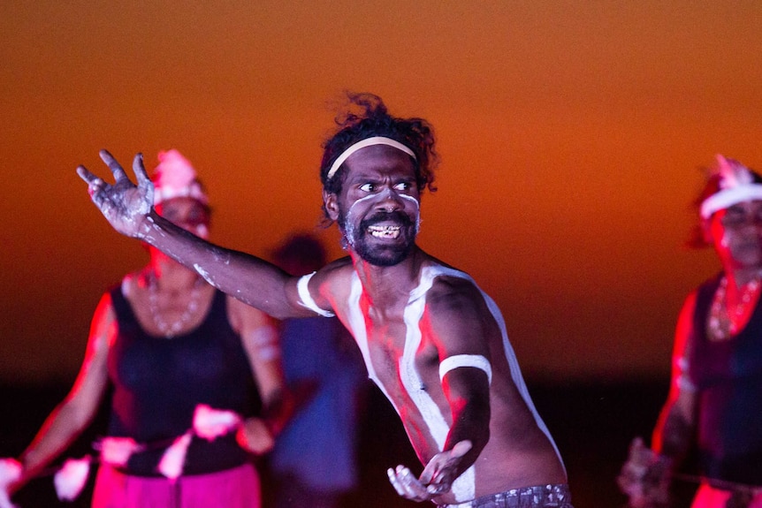 An Indigenous dancer stands, holding a fierce pose.