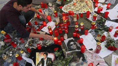 A man in Berlin, Germany, lights a candle at a makeshift shrine to Michael Jackson