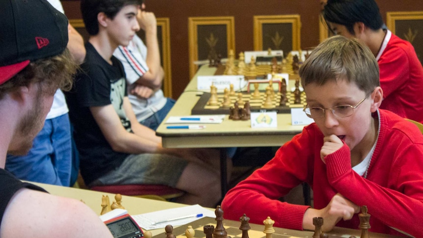 Teenage boys play chess.