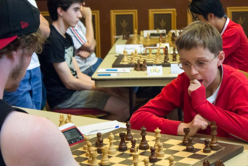 Teenage boys play chess.