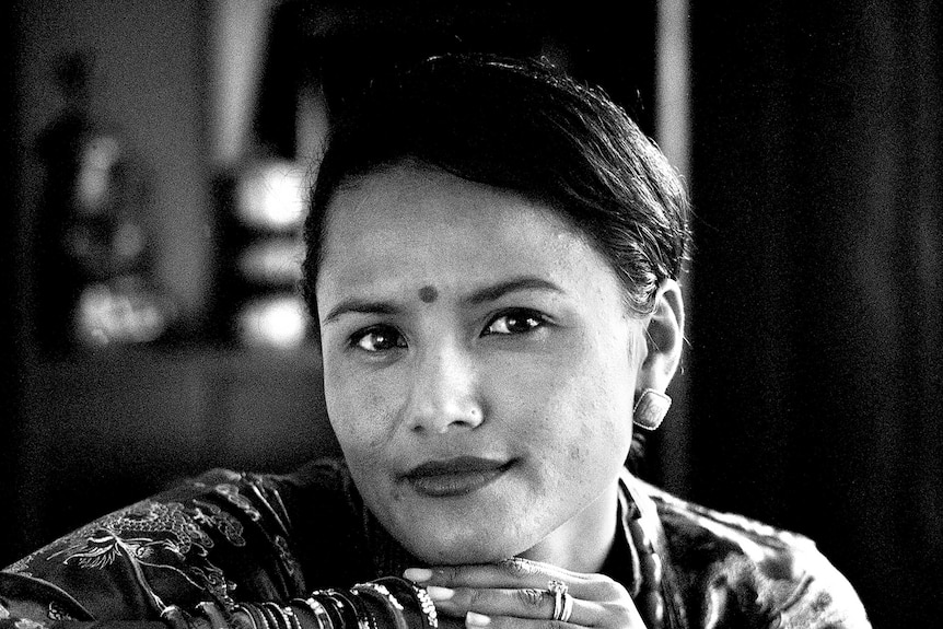 A Nepalese woman rests with her head on her hands