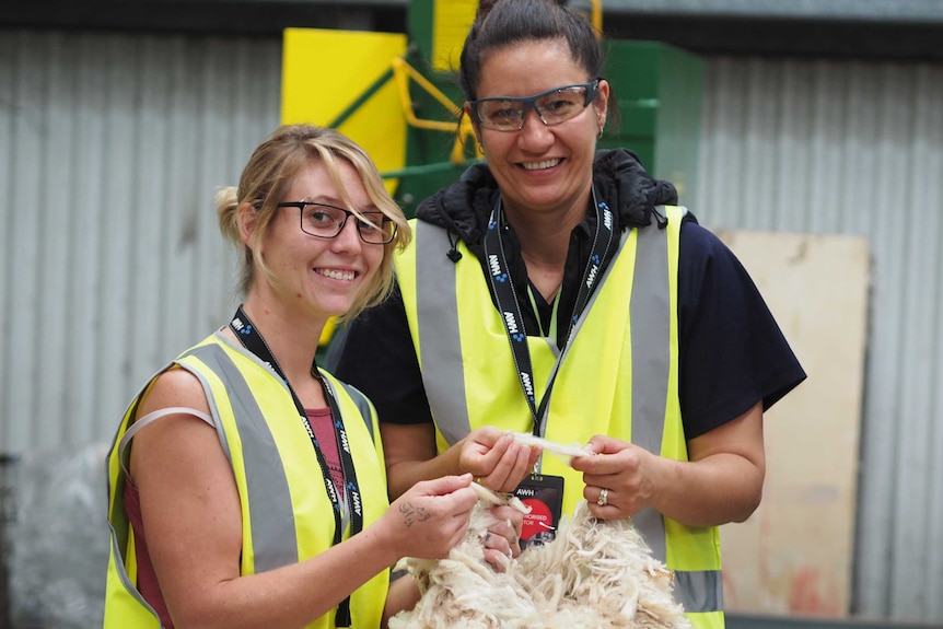 Evynn Roberts and Kursha Oster hold a piece of wool in a factory