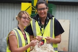 Evynn Roberts and Kursha Oster hold a piece of wool in a factory