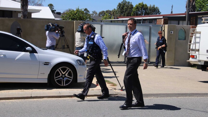 Plain clothes detectives and media crews outside the Club Deroes bikie clubhouse, dominated by a big metal gate.