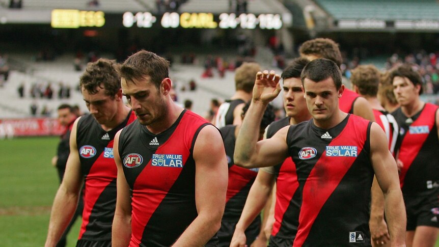 Essendon players walk off the MCG after the team's 96-point thumping by Carlton.