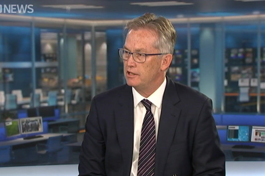 David de Carvalho, in a suit and tie, speaks in a television studio.