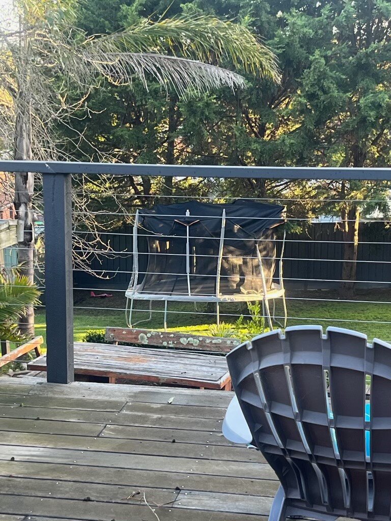 A trampoline pictured in a backyard.