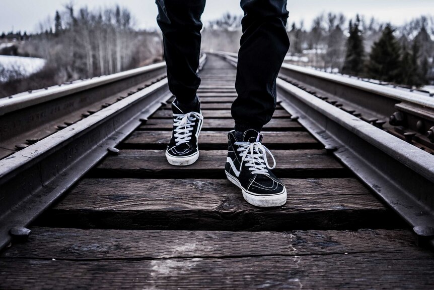 Close up of a person walking on the train tracks