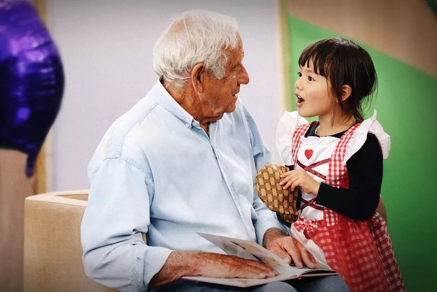 An old man listens to a young girl.