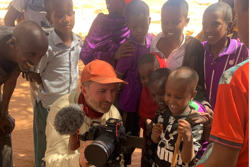 Man showing small children his camera and they look at the images recorded.