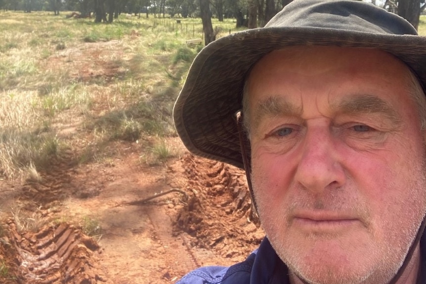 A farmer takes a selfie in a paddock.