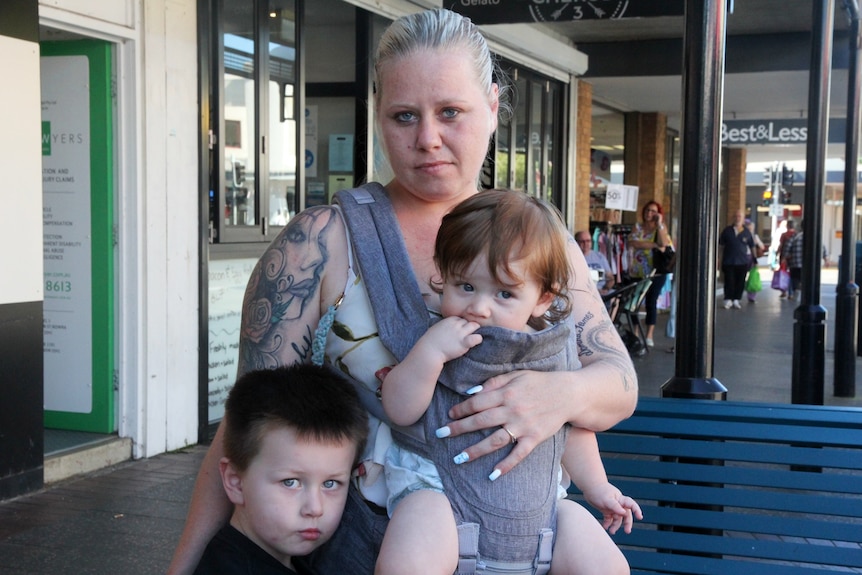 Woman with a baby in a baby carrier and a small child by her side.