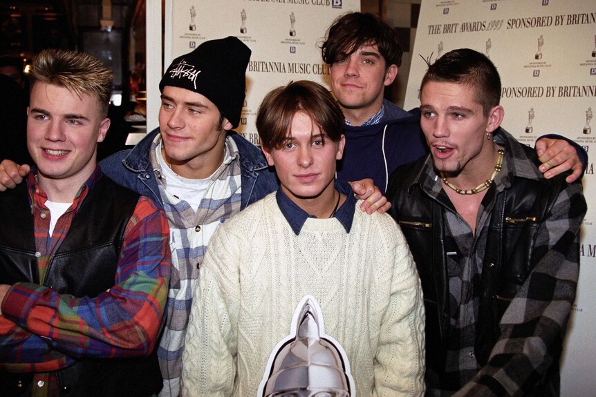 Members of the UK boy band Take That pose for the camera, with Robbie Williams standing in the back.