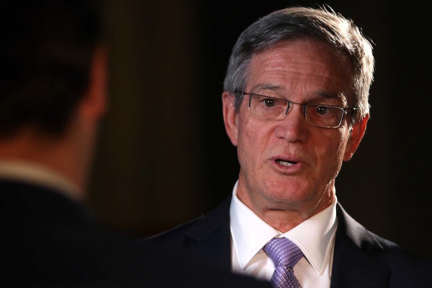 A headshot of Mike Nahan against a black background.