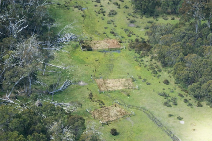 An aerial shot of a valley with fenced of areas that are filled with grass
