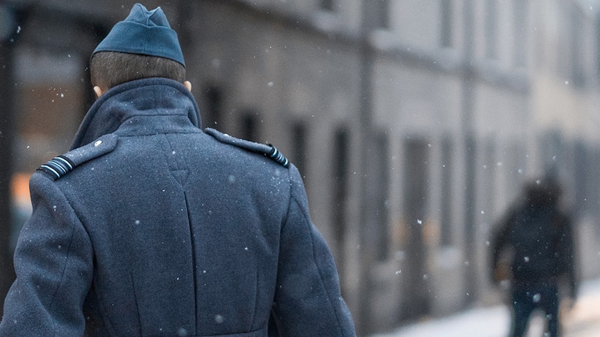 A photograph of the back of a contemporary solider walking through the snow in Cambridge, United Kingdom.
