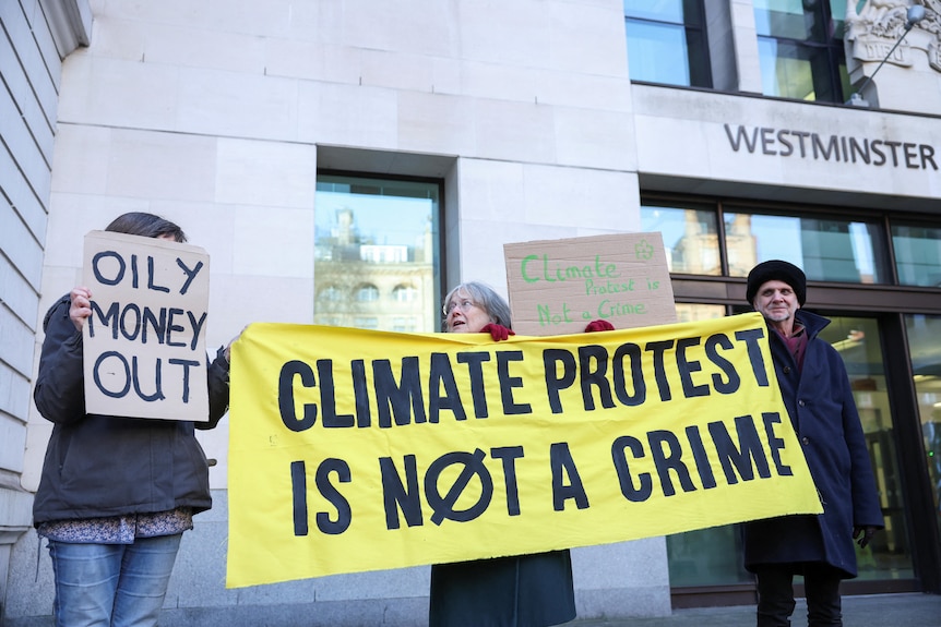 Protesters outside a court house with signs reading "climate protest is not a crime". 