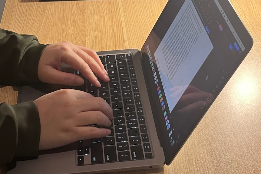 a pair of hands type on a laptop computer.