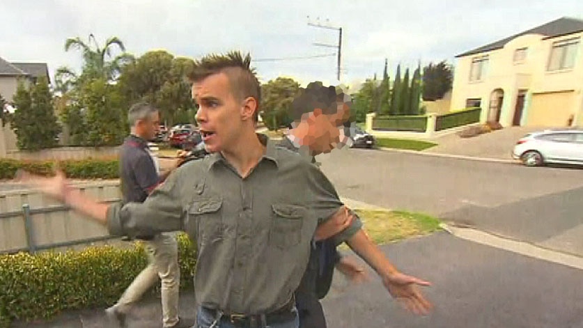 Security personnel pull a protestor away from a press conference being held in suburban Adelaide.