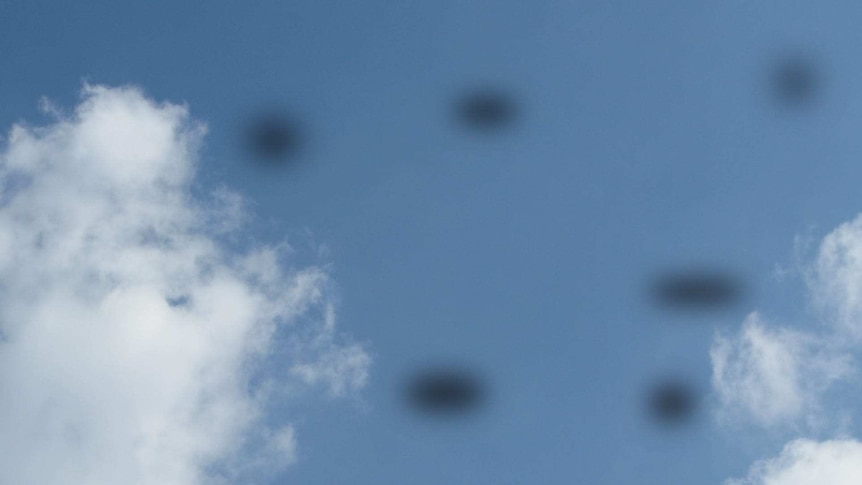 A blue sky with black dot "floaters".