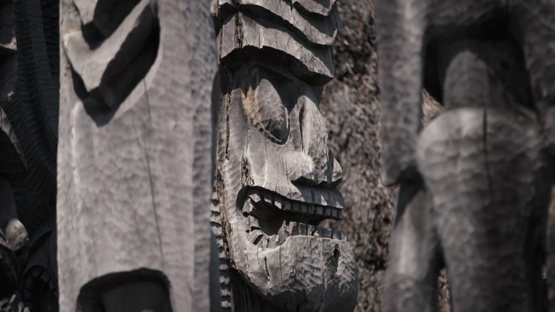 A number of sacred Hawaiian wood carvings with faces clustered together. 