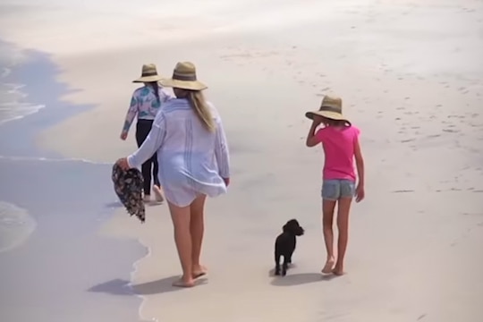 Mum and two daughters walking on the beach.