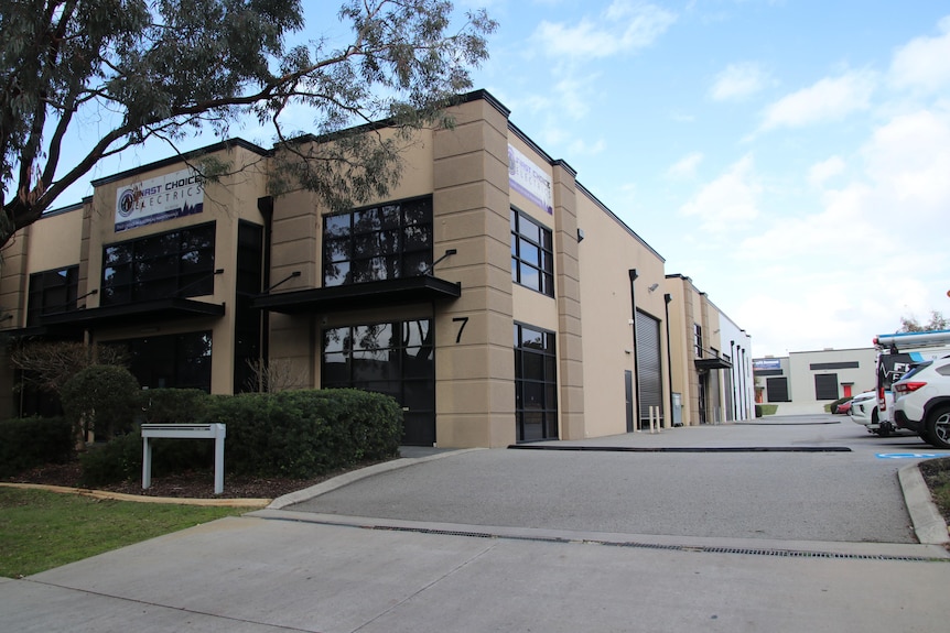 A block of light industrial workshops/offices with a long driveway and roller doors down the site.