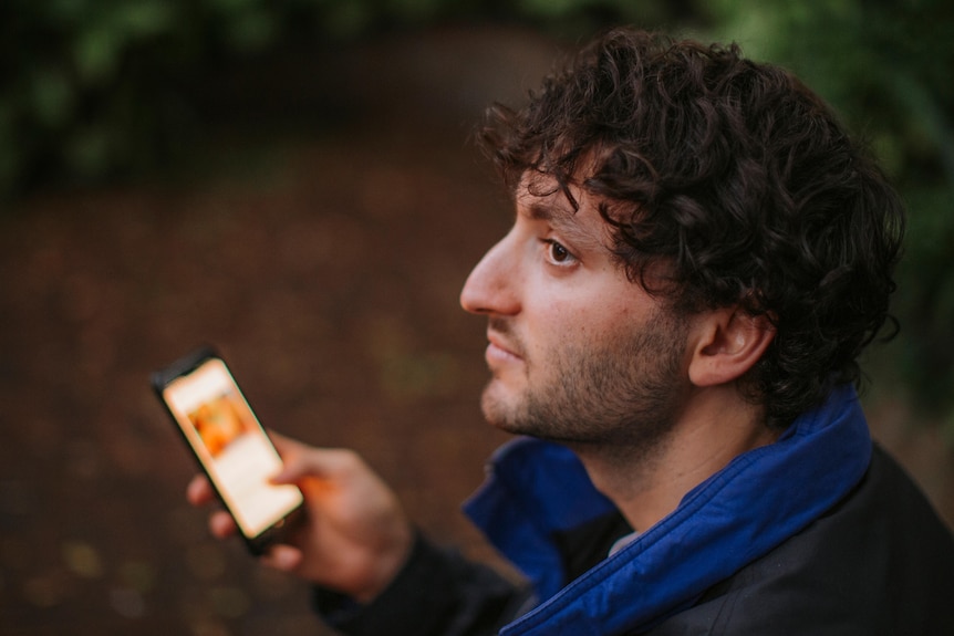 Over the shoulder shot of young man Alexi Barnstone on a dating app on his mobile phone.