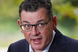 Daniel Andrews looks to his left as he delivers a press conference in a garden.